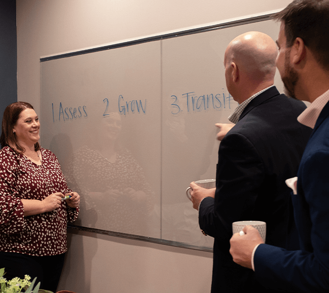 two men and one woman writing on whiteboard